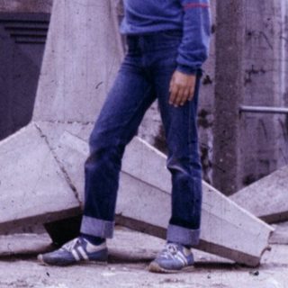 Person holding large concrete slab near old concrete structure.