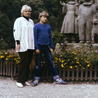 Two people standing beside a family statue in a garden.
