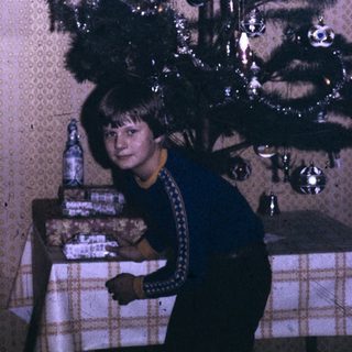 A person sitting beside a decorated Christmas tree.