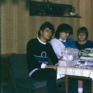 Group gathered around wrapped gift boxes indoors.