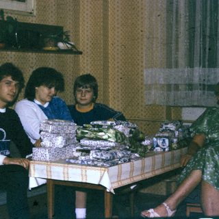 Group gathered around wrapped gift boxes indoors.