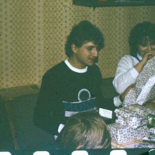 Two people sitting indoors, eating cake.