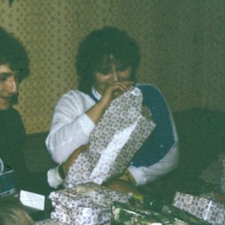 Two people sitting indoors, eating cake.