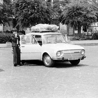Vintage cars parked with luggage, people standing outside.