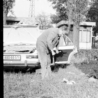 People setting up a tent near a parked car.
