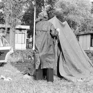 People setting up a tent near a parked car.