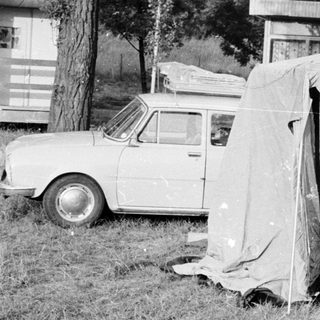 People setting up a tent near a car.