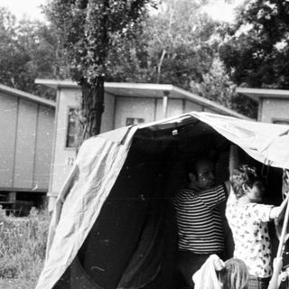 Family pitching tent in grassy campsite area.