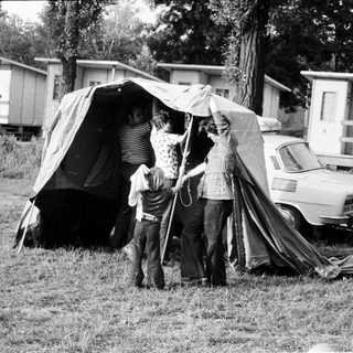 Family pitching tent in grassy campsite area.