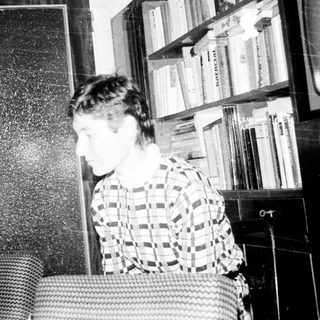 Two people in a dimly lit room with bookshelves.