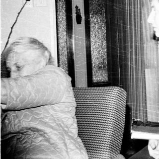 Old woman reading in living room with dog.