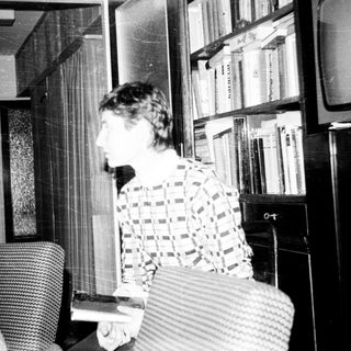 Old woman reading in living room with dog.