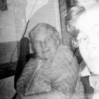 Vintage photo of elderly woman holding young child indoors.