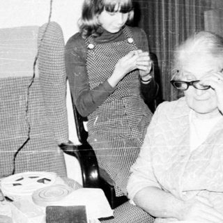 Family gathering around a table with elderly woman.