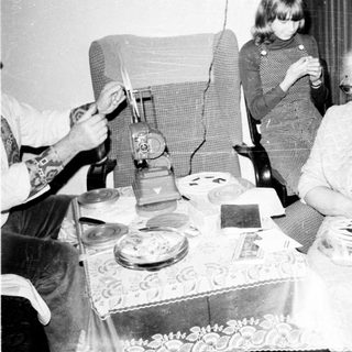 Family gathering around a table with elderly woman.