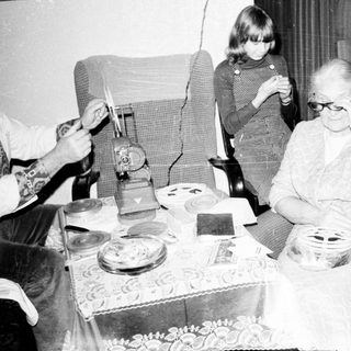 Family gathering around a table with elderly woman.