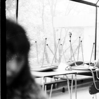 Empty classroom with desks, chairs, and standing microphones.
