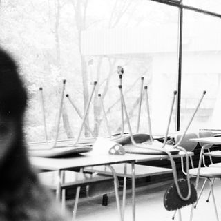 Empty classroom with desks, chairs, and standing microphones.