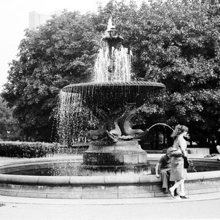 Vintage fountain with people relaxing around it.