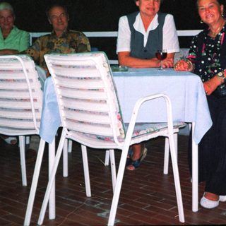 Group of four people dining outdoors at night.