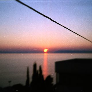 Sunrise or sunset over water with silhouetted horizon.