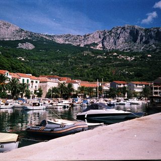 Coastal harbor town with boats and mountains.