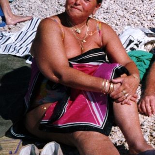 People relaxing on beach towels at a pebble beach.
