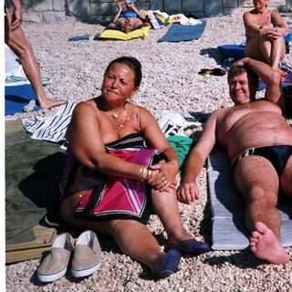 People relaxing on beach towels at a pebble beach.