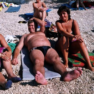 People relaxing on beach towels at a pebble beach.
