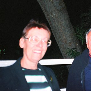 Two people smiling outdoors at night.