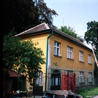Rural house with yellow facade, leaning utility pole.