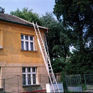 Yellow building with ladder against roof.