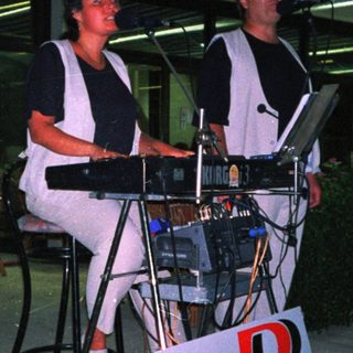 Two musicians performing with keyboards outdoors.