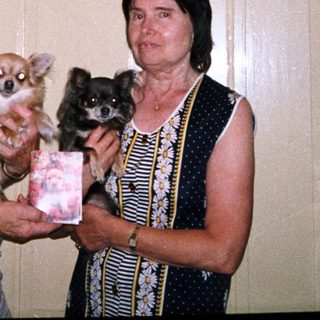 Two people holding small dogs indoors.