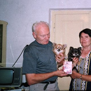 Two people holding small dogs indoors.