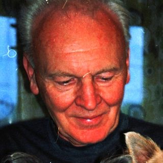 A man holds two small dogs indoors.