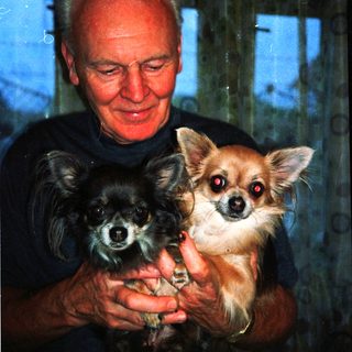 A man holds two small dogs indoors.
