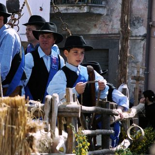 Traditional rural festival with men carrying harvest tools.