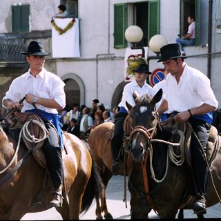 Riders in traditional attire parade on horseback.