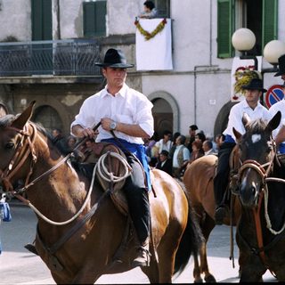 Riders in traditional attire parade on horseback.