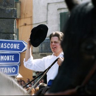 Man holding hat, pointing toward road signs in Italy.