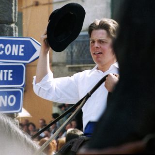 Man holding hat, pointing toward road signs in Italy.