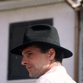Man in traditional hat and white attire outdoors.