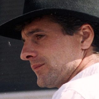 Man in traditional hat and white attire outdoors.