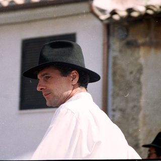 Man in traditional hat and white attire outdoors.