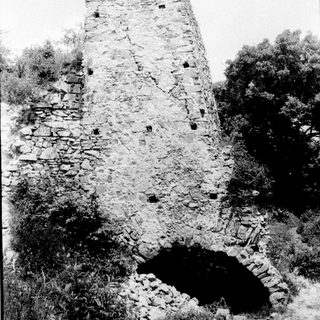 Ruins of a tall stone tower with arched openings.