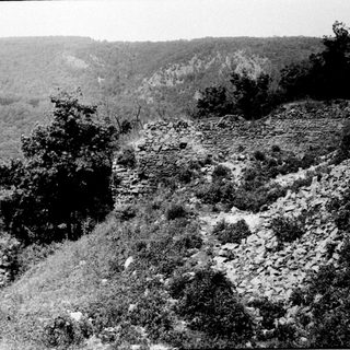 Ancient stone ruins in forested hilly landscape.