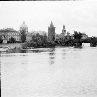 Old photograph of Prague's Charles Bridge and city skyline.