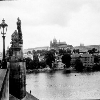 Historic stone bridge with statues over river in Prague.