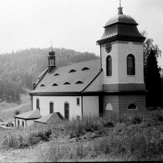 Small rural church with bell tower in hilly landscape.